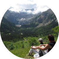 2 persons siting in front of a moutain landscape